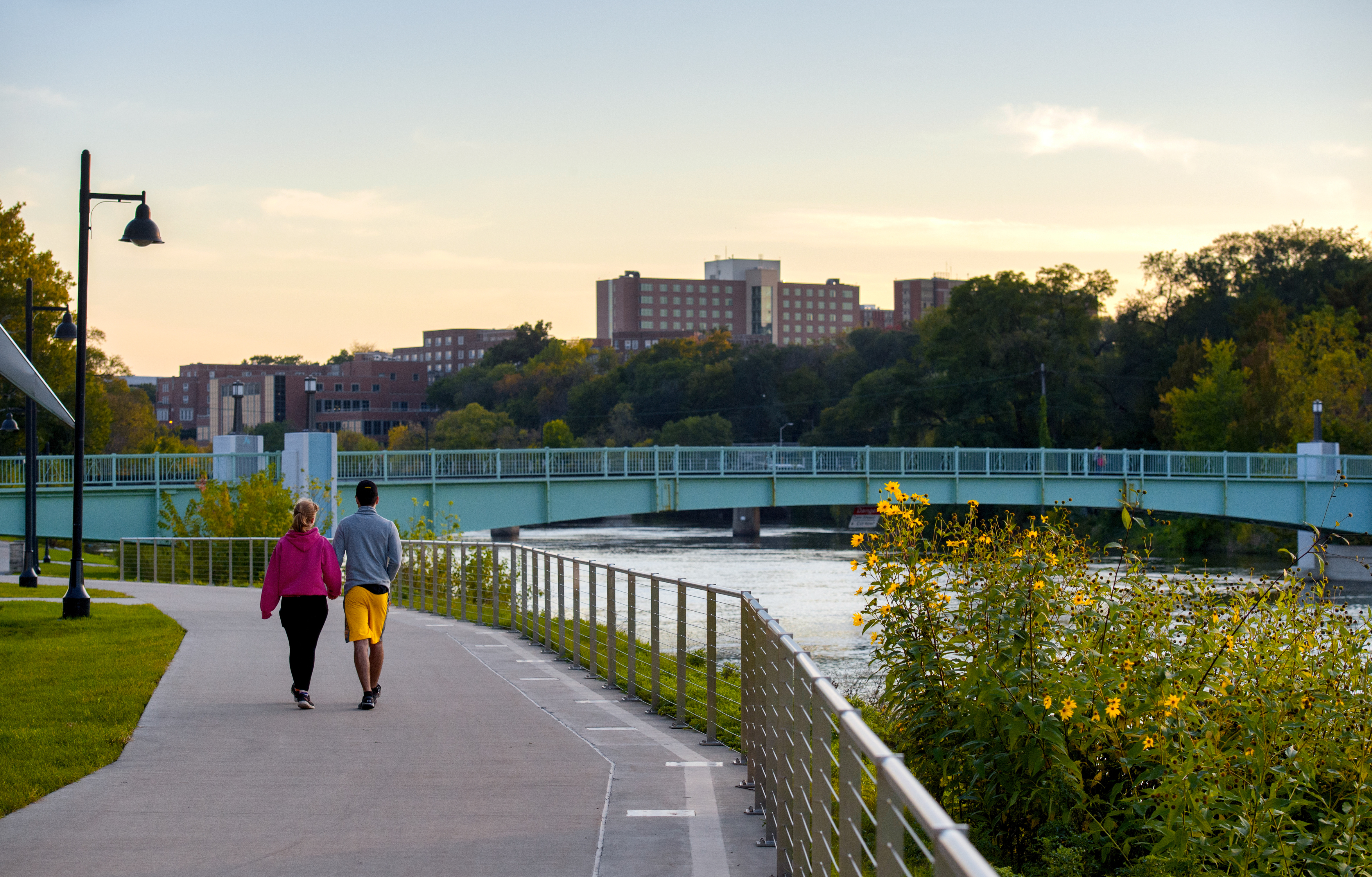 Pedestrians Walking by River at Sunset