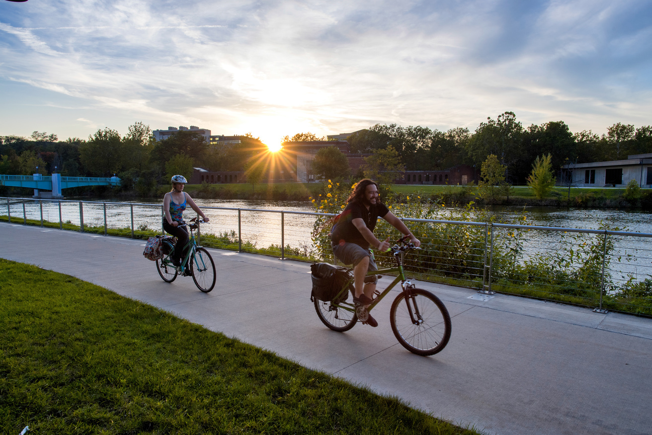 Bikers Behind IMU by River at Sunset